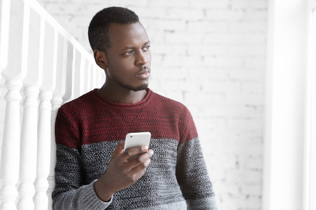 사려 깊은 젊은 아프리카 작가의 실내 촬영, 자신의 휴대 전화에 메모 만들기