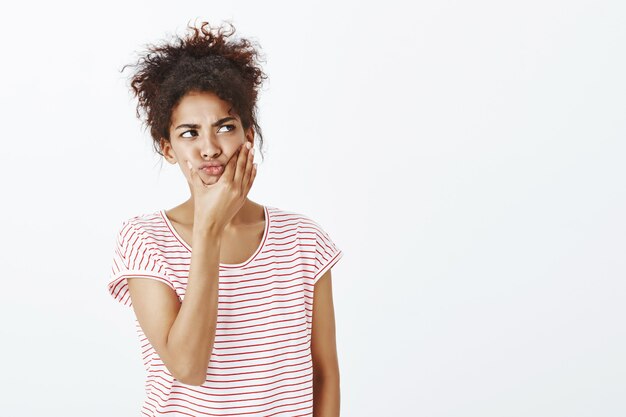 Indoor shot of thougtful woman with afro hairstyle posing in the studio