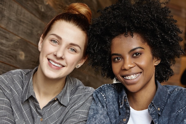 Free Photo Indoor shot of two happy beautiful lesbians of different
