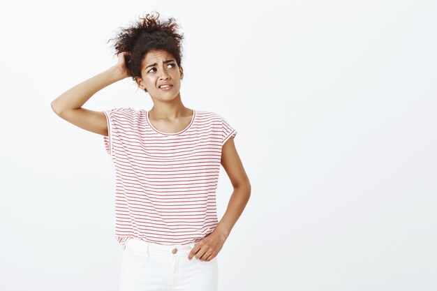 Indoor shot of unsure woman with afro hairstyle posing in the studio