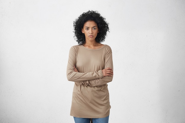 Indoor studio shot of angry young dark-skinned housewife in casual clothes