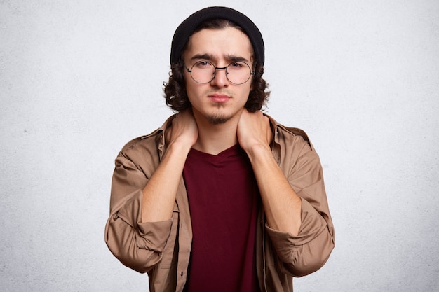 Indoor studio shot of handsome serious young guy posing isolated over white