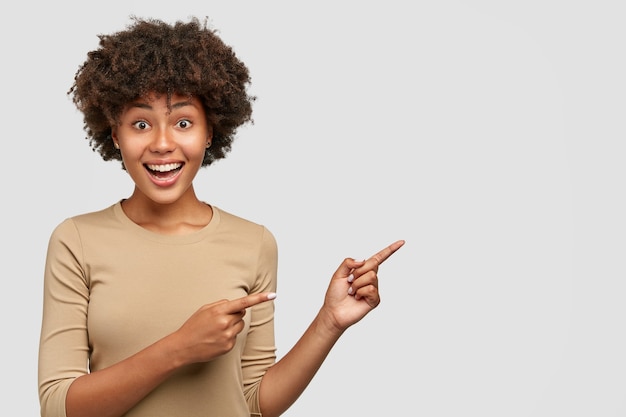 Indoor view of cheerful emotive ethnic young woman with satisfied expression