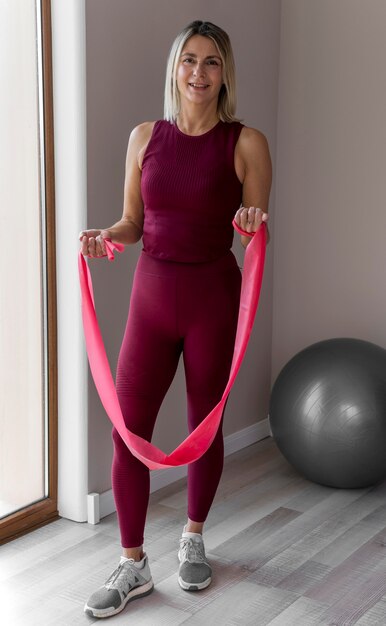 Indoors mature woman doing cardio exercises long shot