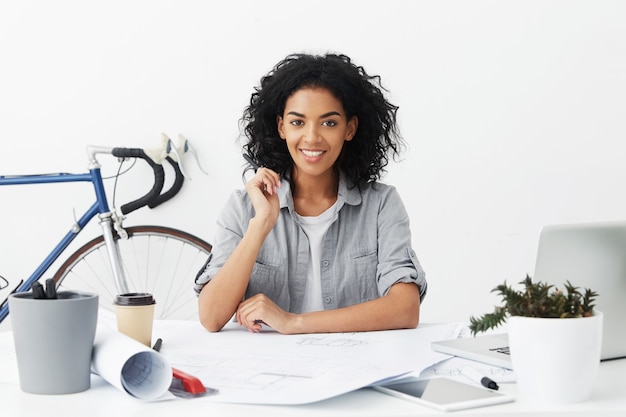 Indoors waist up portrait of joyful self-determined young woman engineer feeling happy