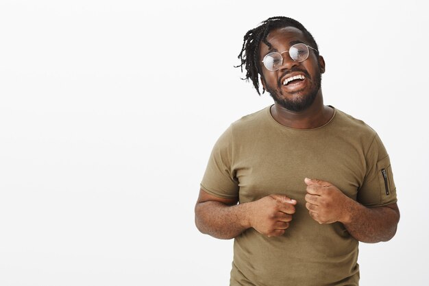 Indor shot of cheerful guy with glasses posing against the white wall