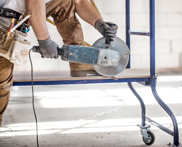 Foto gratuita il costruttore industriale lavora con una smerigliatrice angolare professionale per tagliare mattoni e costruire pareti interne. elettricista.