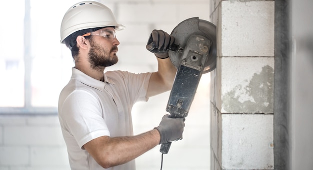 Foto gratuita il costruttore industriale lavora con una smerigliatrice angolare professionale per tagliare i mattoni.