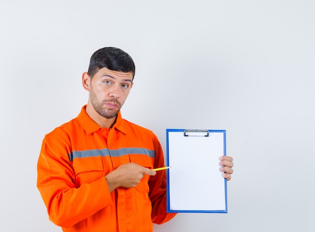 Промышленный человек указывая карандашом в буфер обмена в униформе, вид спереди.
