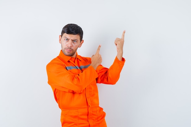 Free photo industrial man pointing up in uniform and looking serious , front view.