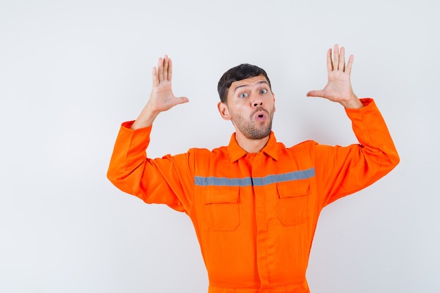 Industrial man raising hands in puzzled gesture in uniform , front view.