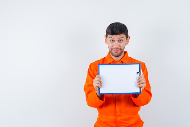 Industrial man in uniform holding clipboard and looking cheery , front view.