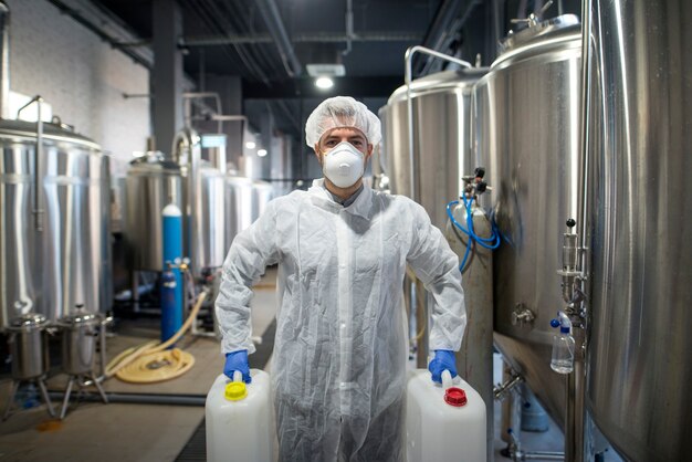 Industrial worker holding plastic cans with chemicals in production plant