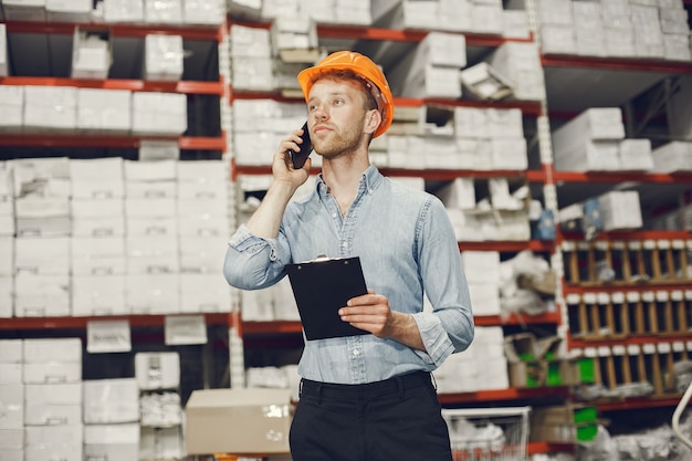 Foto gratuita operaio industriale al chiuso in fabbrica. uomo d'affari con elmetto arancione. uomo in una camicia blu.