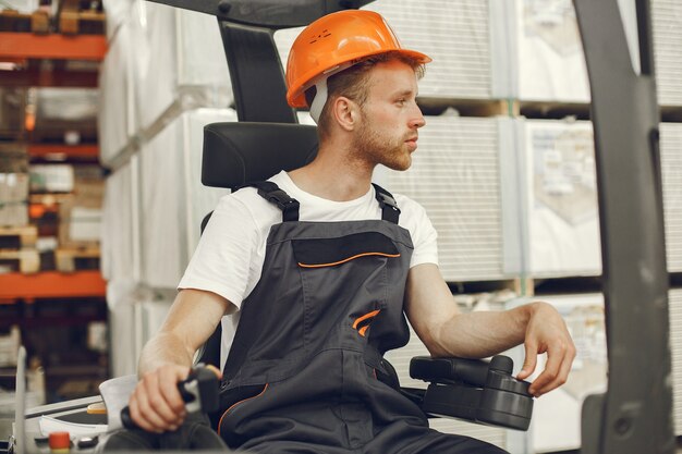 Industrial worker indoors in factory. Young technician with orange hard hat.