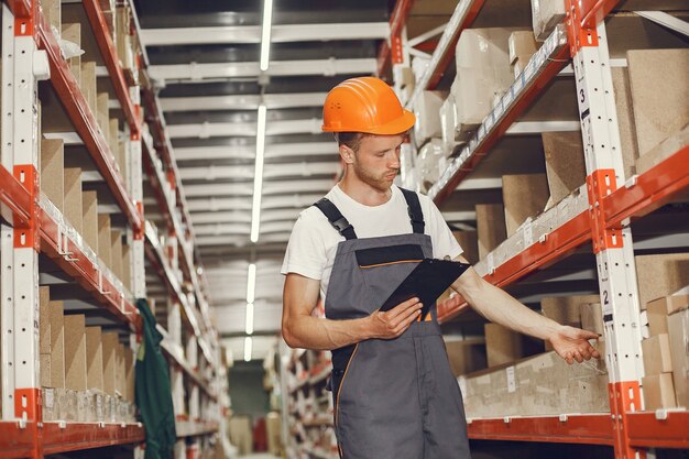 Industrial worker indoors in factory. Young technician with orange hard hat.