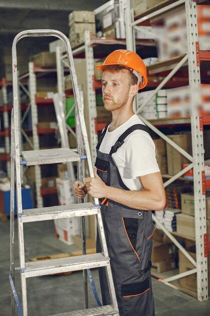 工場の屋内の産業労働者。オレンジ色のヘルメットをかぶった若い技術者。