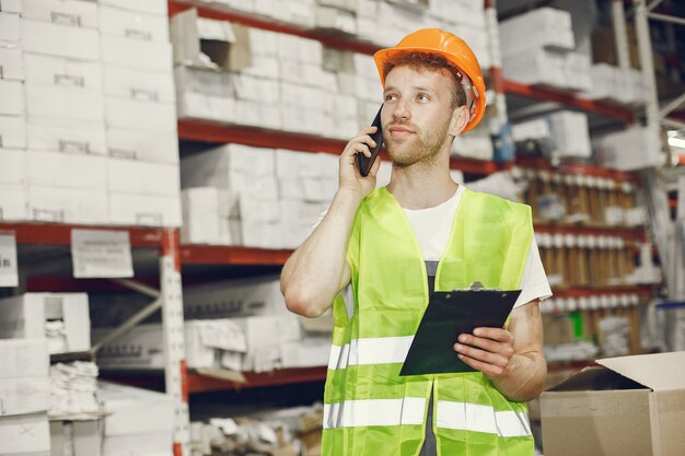 Industrial worker indoors in factory. Young technician with orange hard hat.