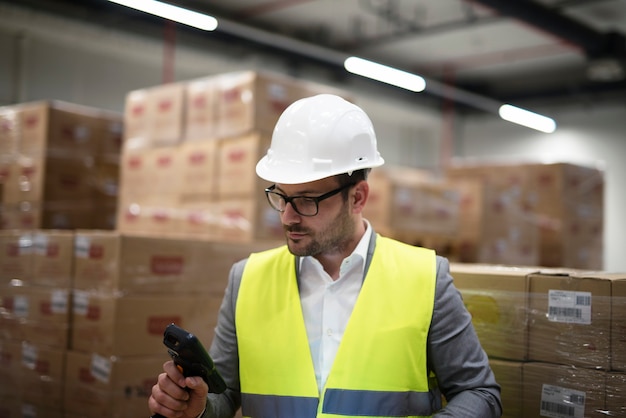 Industrial worker with bar code scanner keeping track and controlling goods arriving in warehouse