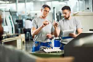 Foto gratuita lavoratori dell'industria che collaborano mentre eseguono il controllo di qualità dei prodotti fabbricati in una fabbrica