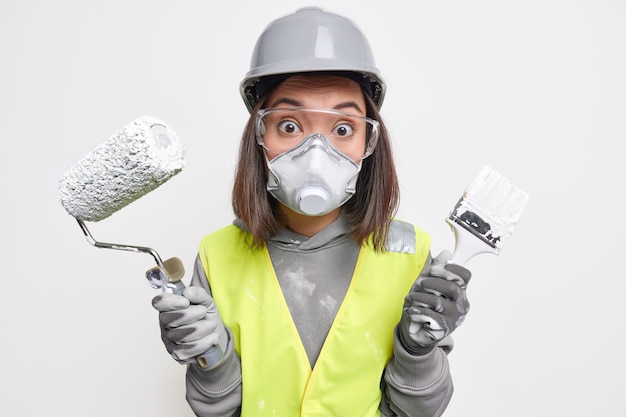 산업 공학 및 건설 개념입니다. 놀란 전문 여성 엔지니어는 건물 유니폼 보호 헬멧 안경 마스크를 착용하고 장갑은 재장식을 위해 페인트 롤러 브러시를 사용합니다