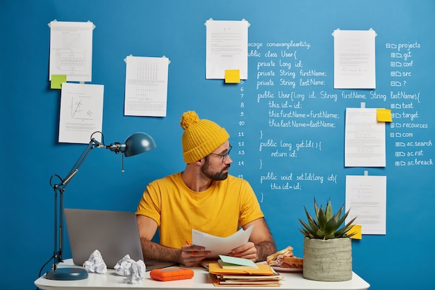 Inexperienced European man looks through paper documents, analyzes during working process