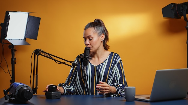 Influencer talking about new camera lens in her weekly podcast review episodes. Content creator new media star on social media talking video photo equipment for online internet web show