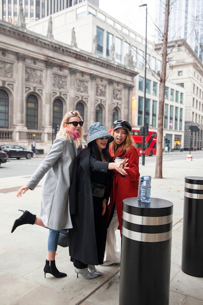 Free photo influencers taking a selfie using a smartphone placed on a pylon in the city