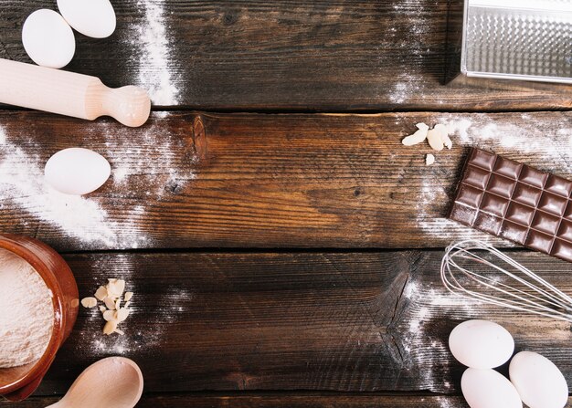 Ingredients for baking cake with rolling pin; whisker and spoon on table