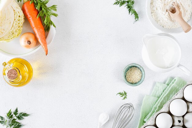 Ингредиенты для пирога с капустой и морковью Капуста морковь яйца мука молоко масло специи на белом фоне
