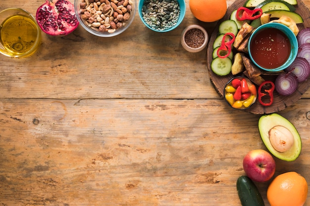 Ingredienti; frutta secca; frutta; olio e verdure a fette sul tavolo di legno