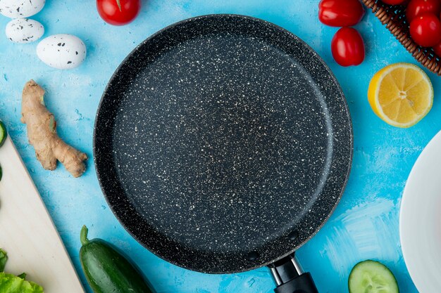 Ingredients and frying pan on blue surface