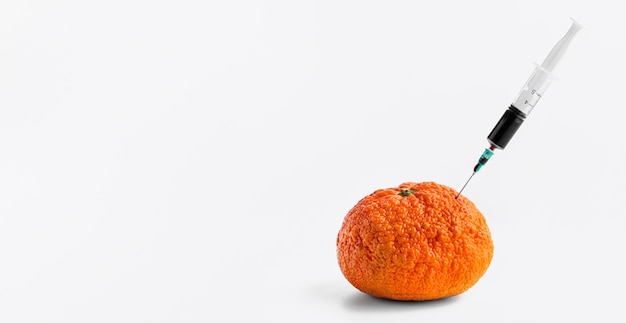 Free photo injecting chemicals into an orange with syringe