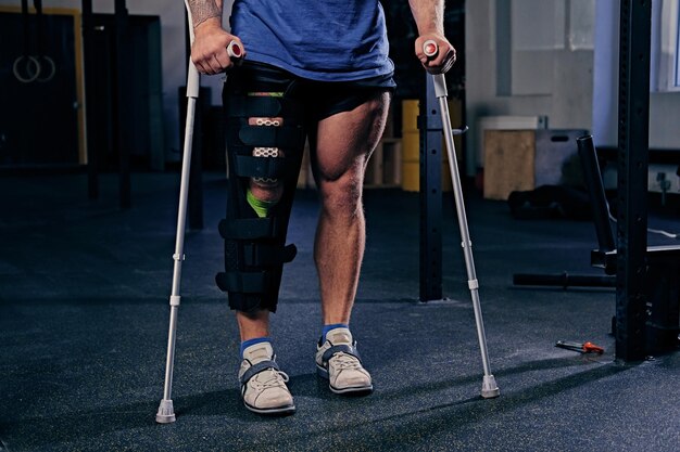 Injured bodybuilder's leg in bandage with crutches.