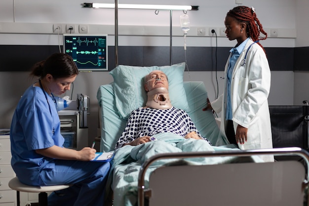 Free photo injured senior man with neck brace laying in bed