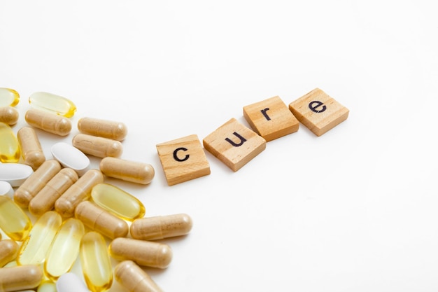 Inscription cure in wooden cubes on a white background of different pills