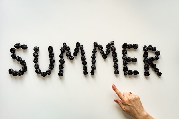 Inscription Summer made with blackberries on white surface