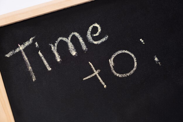 Inscription Time To: on black chalkboard, close up.