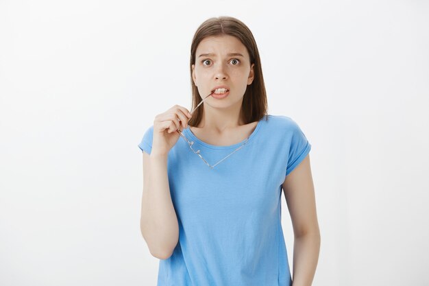 Insecure anxious woman biting glasses temple and looking worried