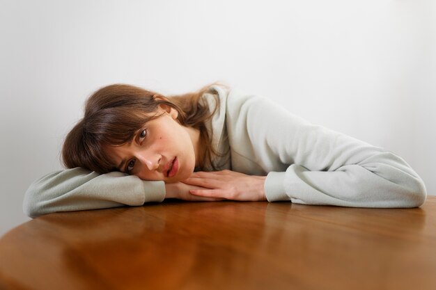 Insecure woman with head on table front view