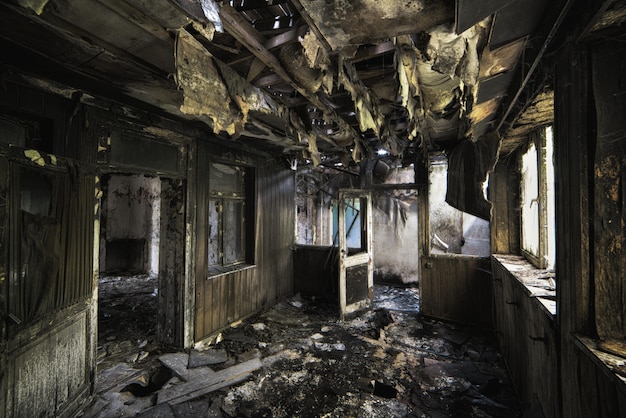 Заброшенное разрушенное здание с обгоревшими стенами и изношенными дверями изнутри.