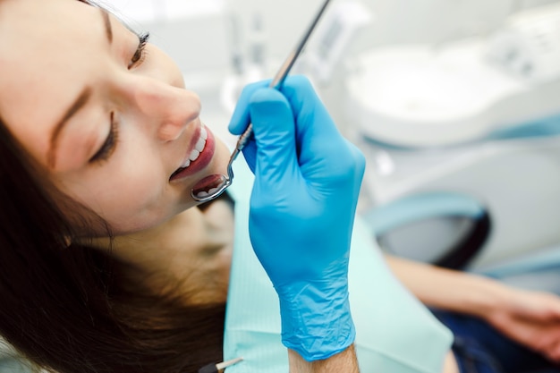 거울의 도움으로 여성의 치아 검사