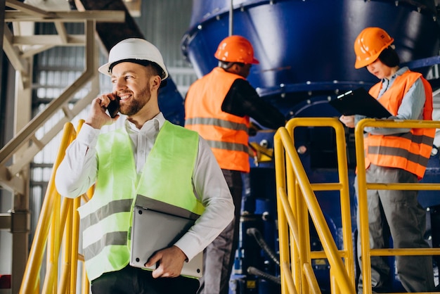 Inspector at a factory talking on the phone while others are working