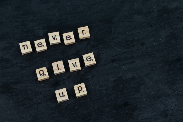 Free photo inspirational quotes on a black board written with wooden dices