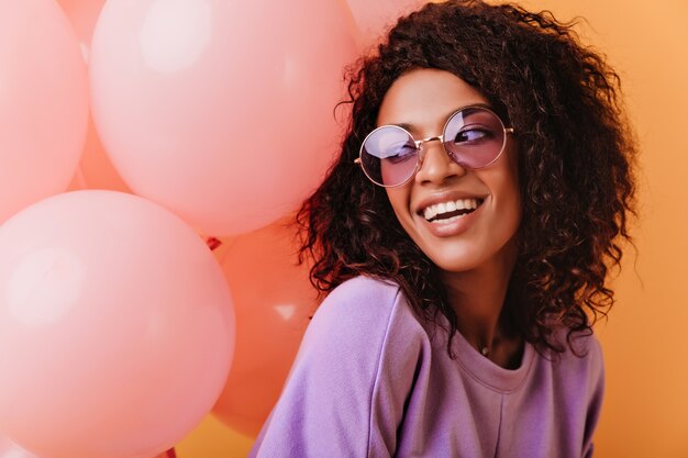 Inspired african girl expressing good emotions in her birthday. blithesome curly lady posing with pink balloons.