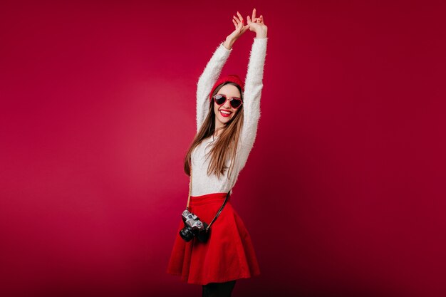 Вдохновленная кавказская девушка танцует с поднятыми руками на бордовом пространстве