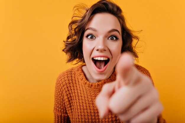 Inspired caucasian girl with trendy hairstyle having fun and pointing finger to camera