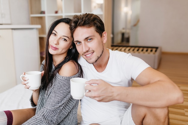 Inspired caucasian man drinking coffee with womanfriend in sunday morning