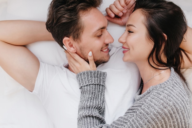 Free photo inspired caucasian woman smiling while holding husband's face in hands