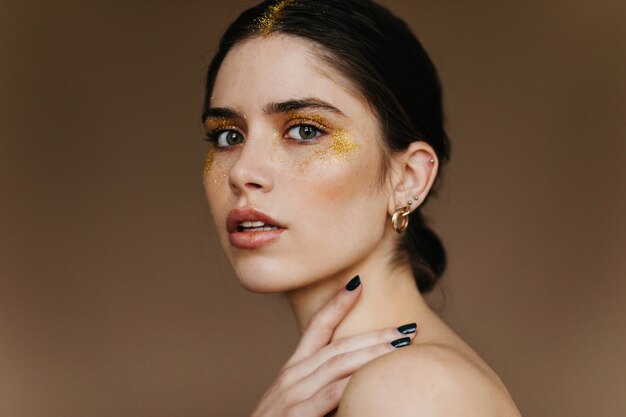 Inspired caucasian woman with party makeup . Close-up photo of fascinating girl with golden eyeshadows.